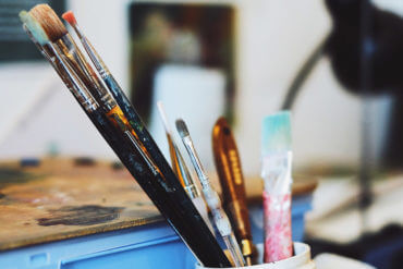 雜亂無章的藝術家工作室在一個舊容器中帶有畫筆